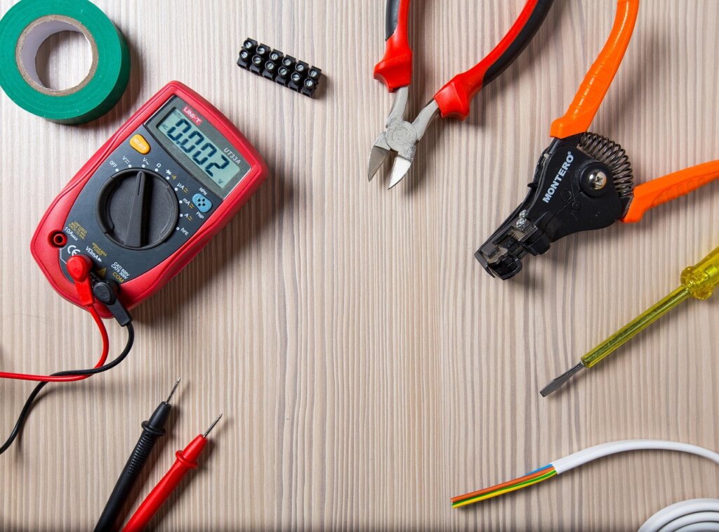 silicone removal tools laid on table — scraper, caulk gun, masking tape