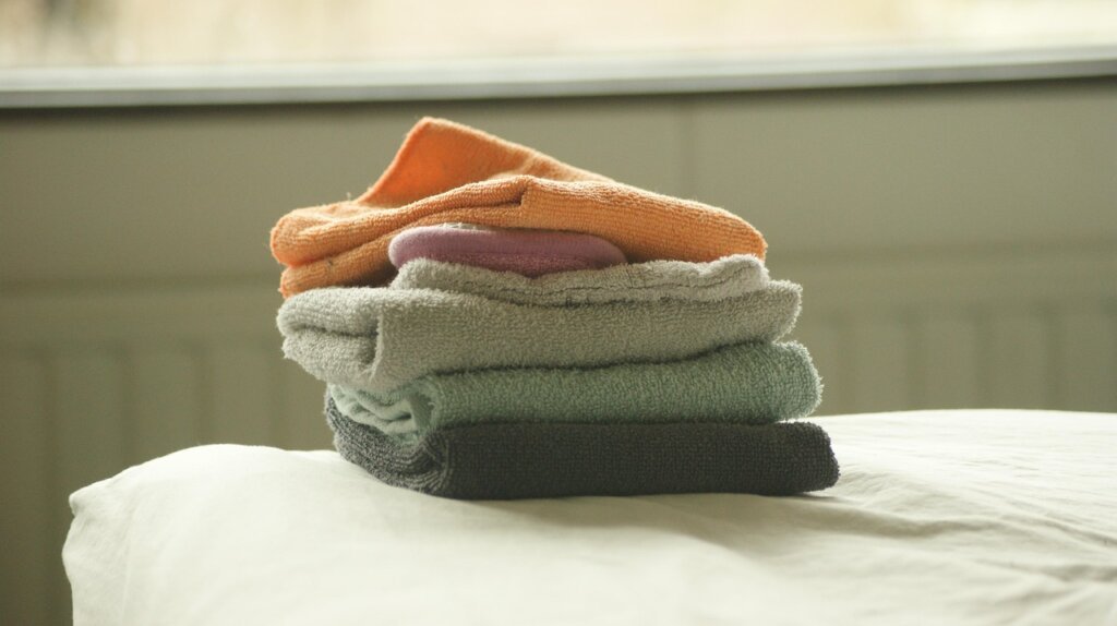 multiple clean kitchen towels stacked neatly in different colors, organized kitchen drawer